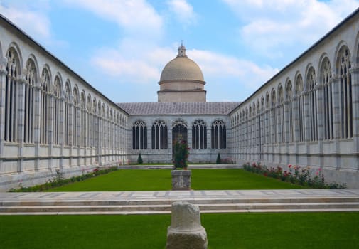Historical courtyard garden with arched building around it and green lawn