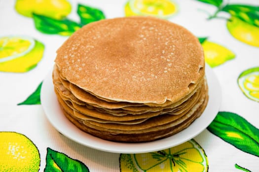 Hill from pancakes on white plate on bright cloth