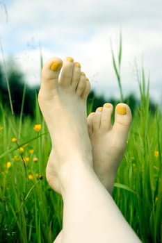 Two female feet against a green juicy grass