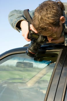 The man with the camera has hidden on a car roof