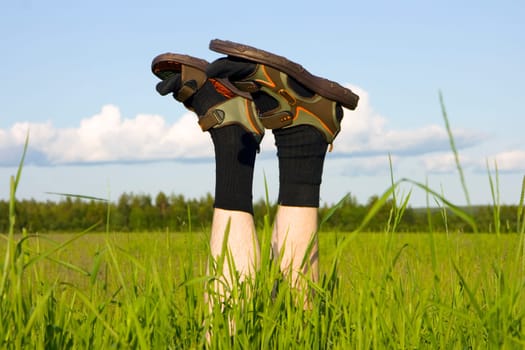 Man's feet sticking out of a green grass