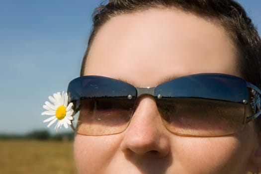 Photo of the girl in sunglasses with a camomile