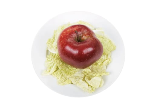 Red apple on salad sheet on a white plate