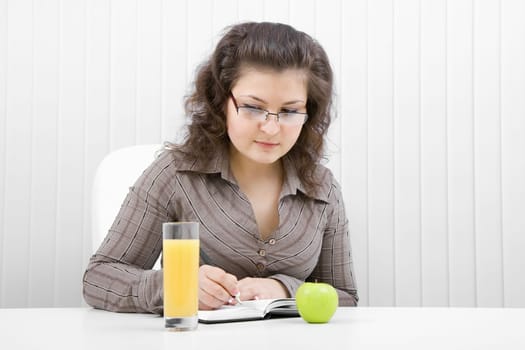 woman manager takes notes. On the table with a glass of juice and apple