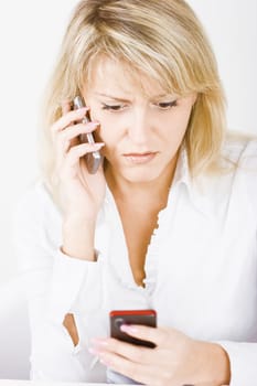 surprised blonde with two mobile phones on a white background