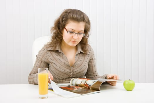 young beautiful girl in the office leafing through a fashion catalog