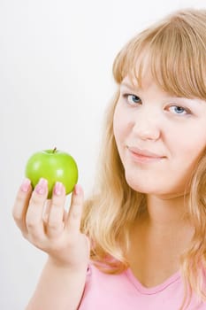 portrait of smiling blonde with green apple on a white background