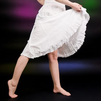 girl in summer dress dancing on a black background