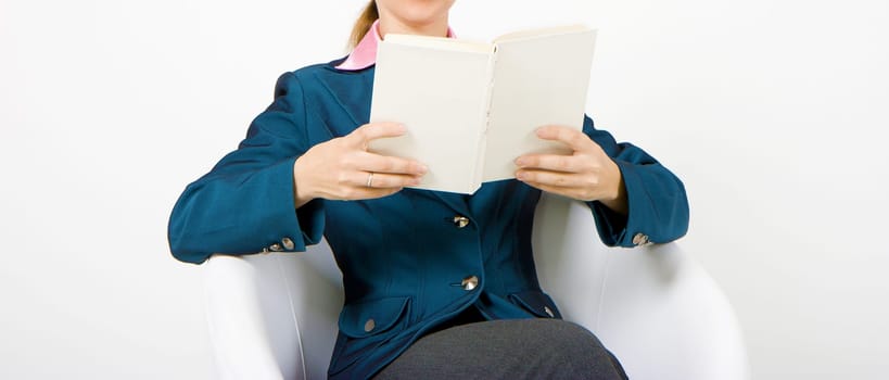 student with a book sitting in white chair