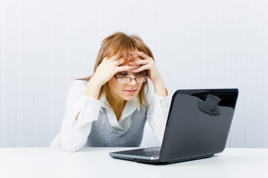 weary worker in the office with a laptop. Girl with glasses