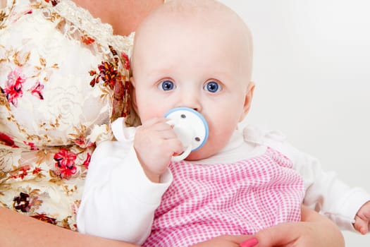 infant with a pacifier in his mother's arms
