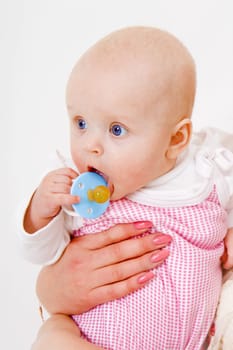 infant with a pacifier in the hands of moms