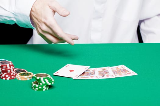 player's hand with cards and poker chips on a green table