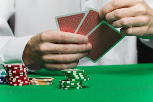 poker chips and the player's hand with the cards on the green game table