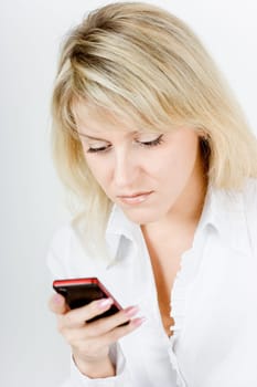 concentrated beautiful blonde girl with the phone on a white background