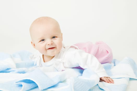 Smiling baby lying on a blue towel. Studio photography