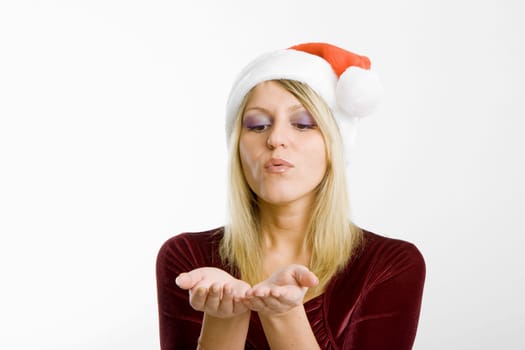 girl in a Christmas hat on a light background is blowing in the palm