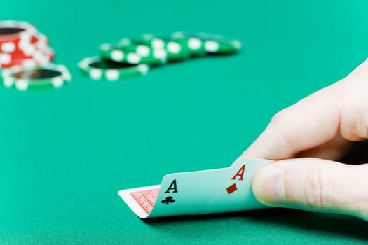 poker player with two aces and chips on a green table