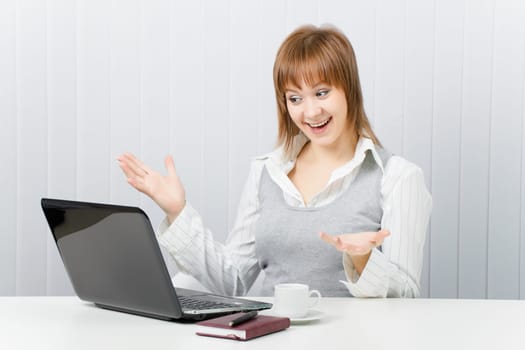 girl in office pleasantly surprised, looking at laptop