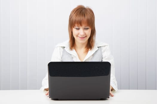 Attractive smiling happy girl with a laptop in the office