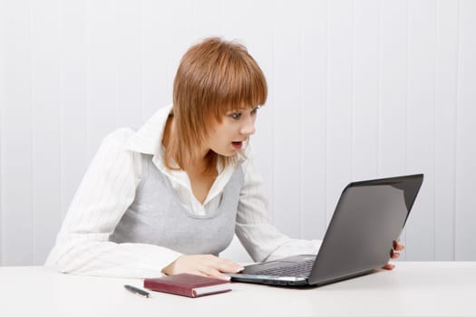 attractive girl with surprise stares at the monitor laptop