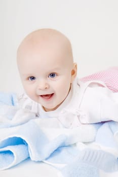 blue-eyed happy baby with a blue towel on the floor