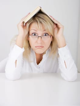 blond girl in glasses hidden under a book