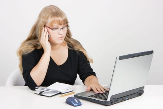 office worker. Blonde girl with laptop talking on a cell phone.
