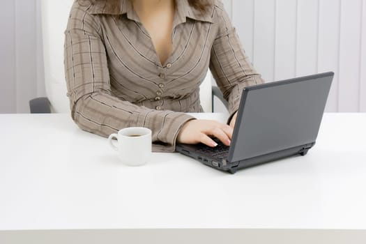 girl with a laptop works in an office. Part of the body