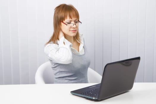 tired worker in the office. Disheveled girl with laptop. neck pain