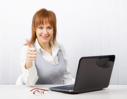 Positive smiling businesswoman with a laptop with a thumb up