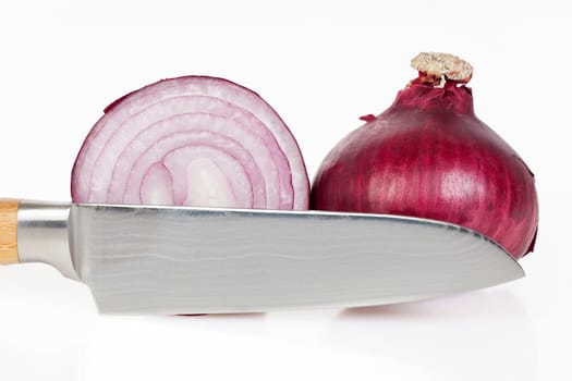 Whole and sliced red onions with knife against a white background