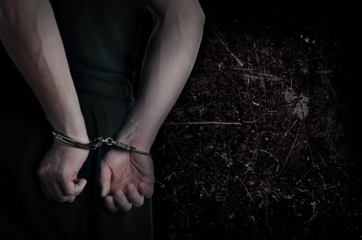 Men with handcuffs and grunge wall in background