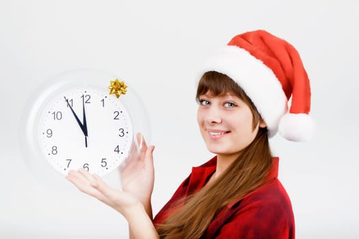 smiling attractive girl in Santa hat with a clock