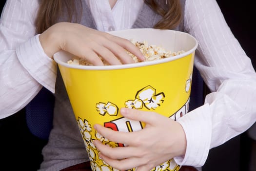child's hand in a bucket of popcorn