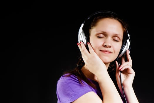 smiling girl with eyes closed in the headphones on a black background