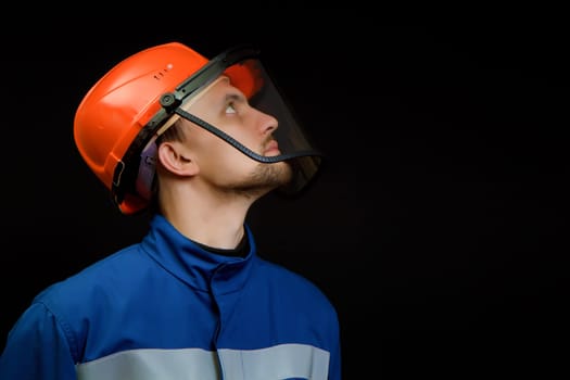 The worker in overalls and a helmet on a black background