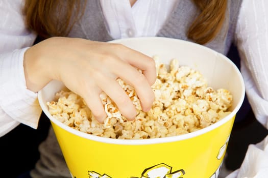 child's hand in a bucket of popcorn