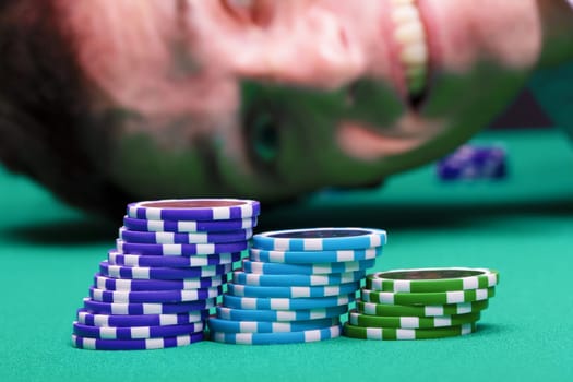 Chips on the background of a happy male face on a green table casino