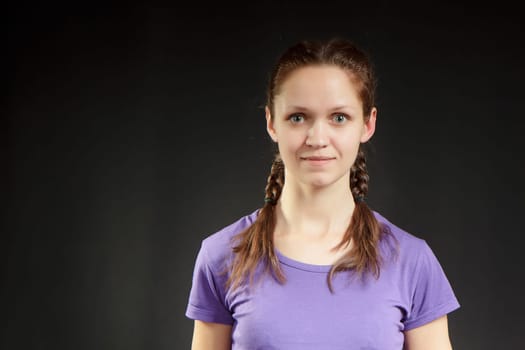 cute girl with pigtails in a T-shirt on a dark background