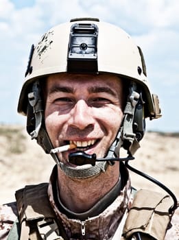 smiling US soldier in the desert smoking a cigarette