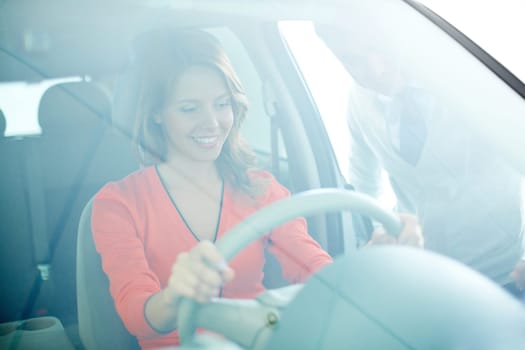 Photo of smiling woman sitting in car with salesman near by