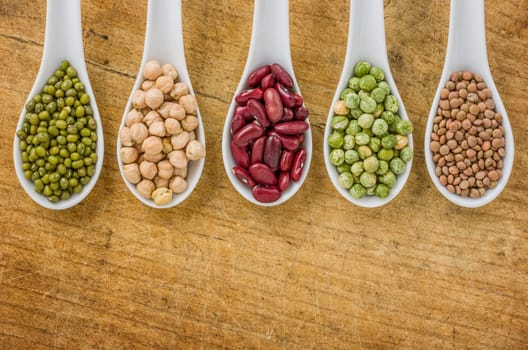 Various legumes on porcelain spoons
