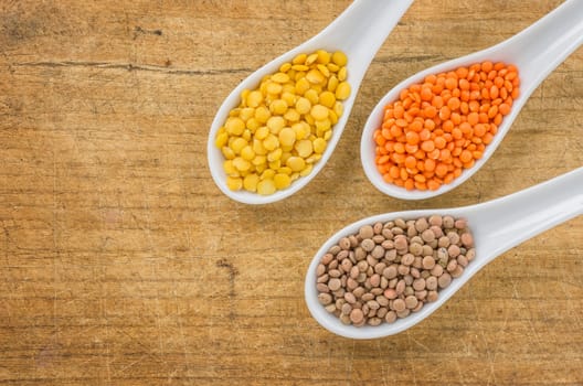Different types of lentils on porcelain spoons