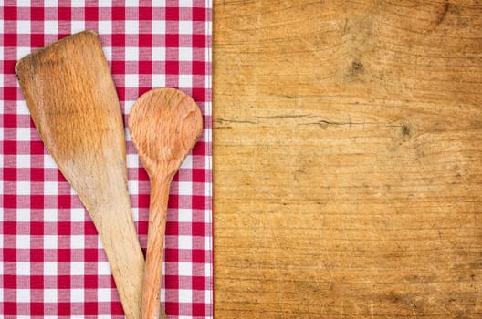 Rustic wooden background with checkered tablecloth and cooking spoon