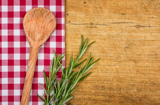 Rustic wooden background with checkered tablecloth and cooking spoon