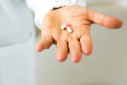 Doctor holding white and pink pills against anxiety on light gray background