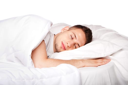 Handsome young man happily sleeping in white bed, isolated.
