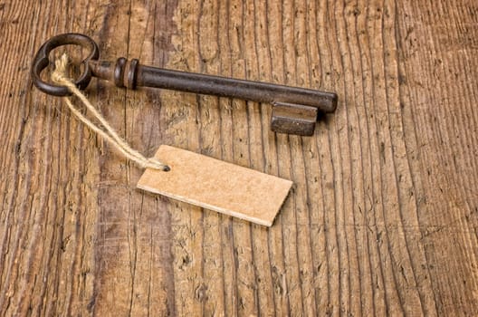 Old key with pendant on a wooden board