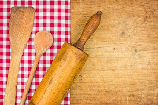 Pasta pin with wooden spoon on a wooden board with checkered tablecloth